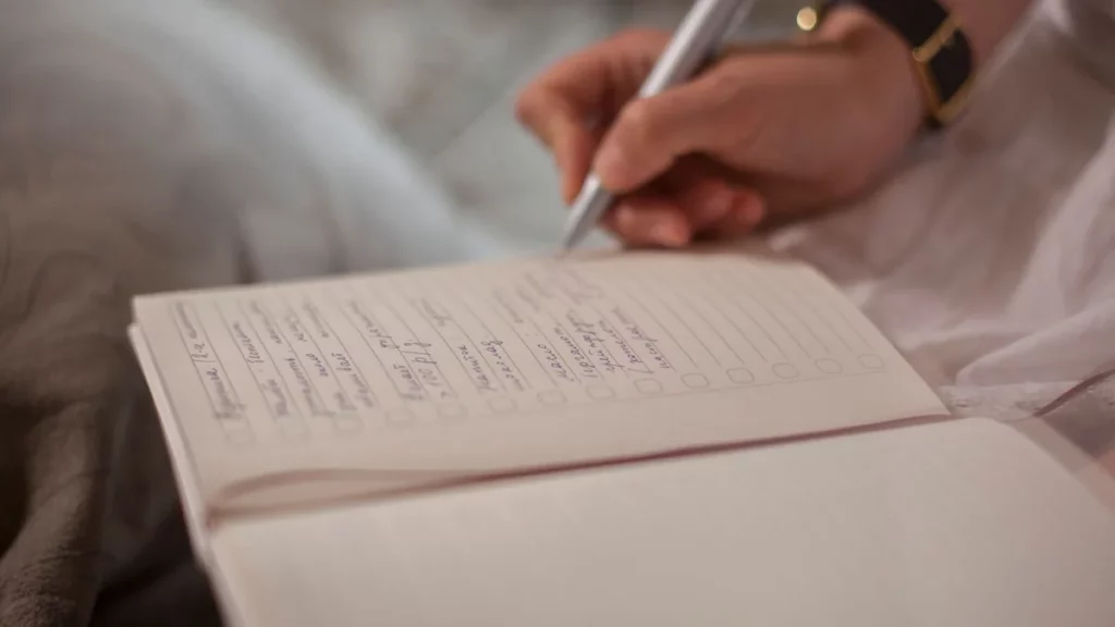 Ręka wypisująca listę kontrolną w notesie
