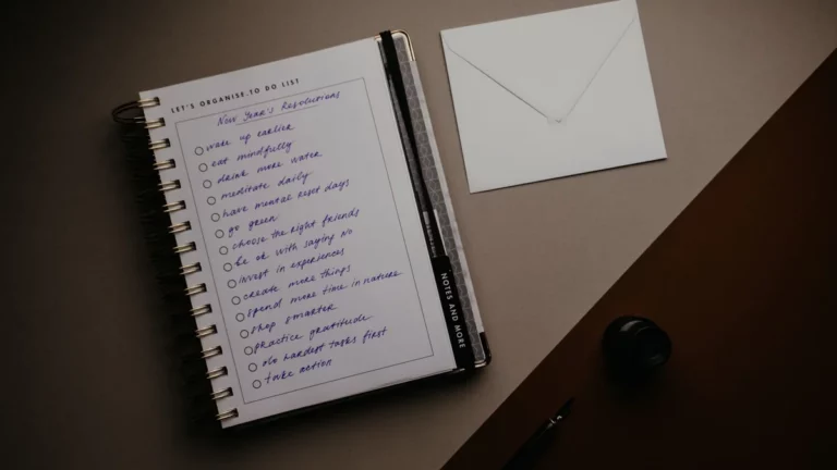 Notes z listą zadań i koperta na biurku